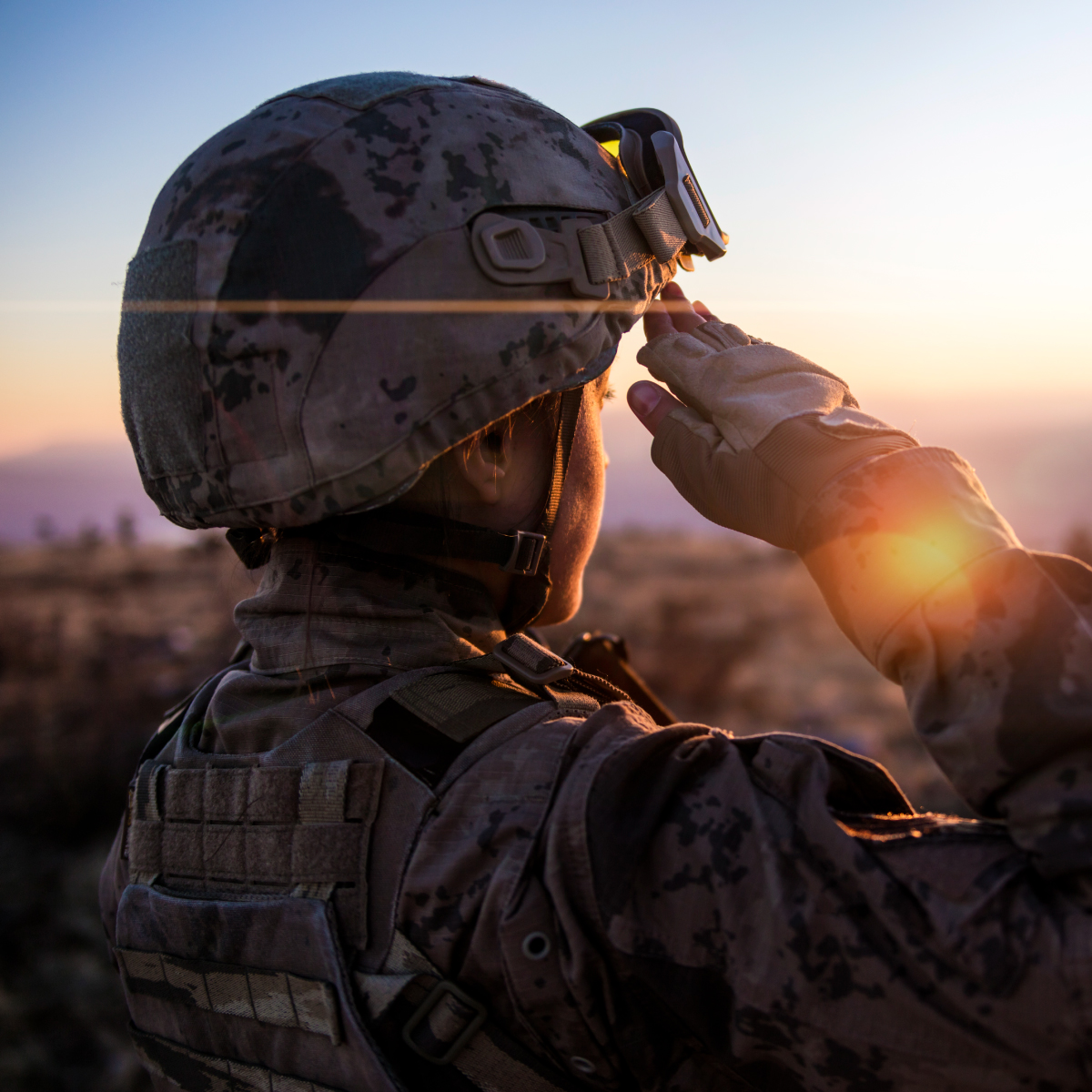 A soldier looking at a sunset on the horizon